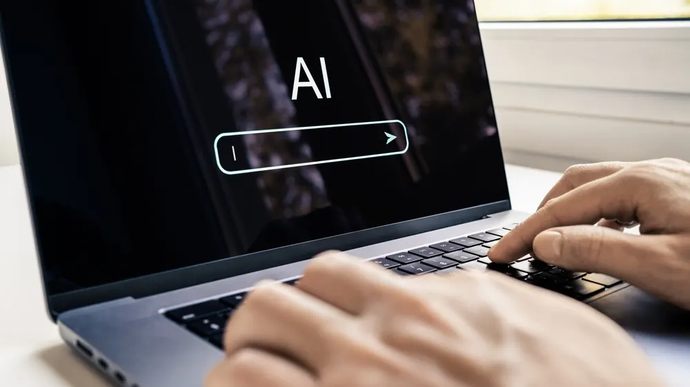 Laptop med ett AI-sökfält och händer som skriver