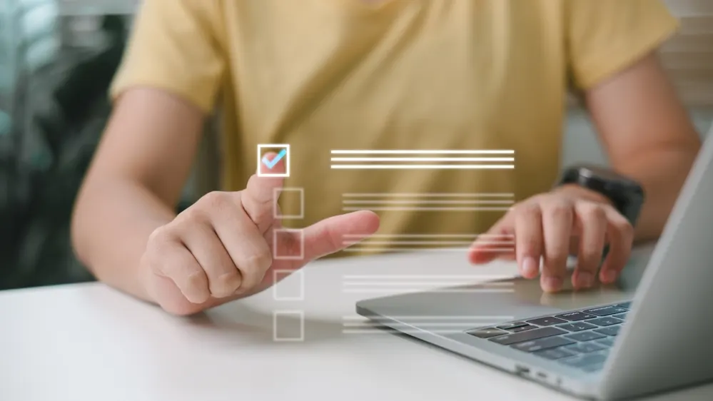 Person som bockar av punkter i en checklista vid en laptop